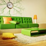 Gaiši zaļš dīvāns un oranži akcenti interjerā
